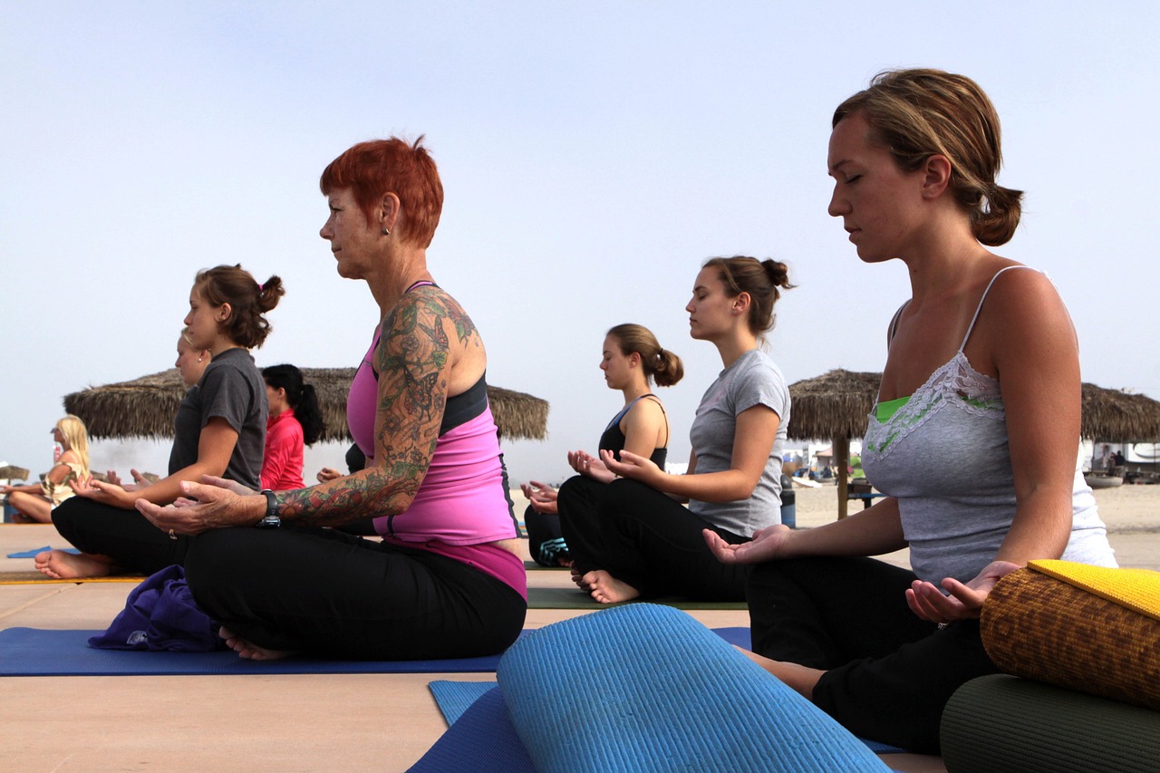 prevenzione dopo i 50 anni: fare yoga aiuta a prevenire la depressione come queste donne che fanno yoga in spiaggia